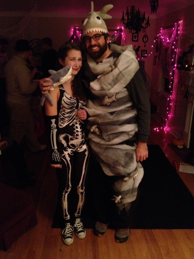 Woman dressed as skeleton poses with man dressed as a Sharknado at a Halloween party.